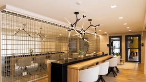 Una cocina moderna con una isla central, asientos tipo bar y un separador metálico decorativo.