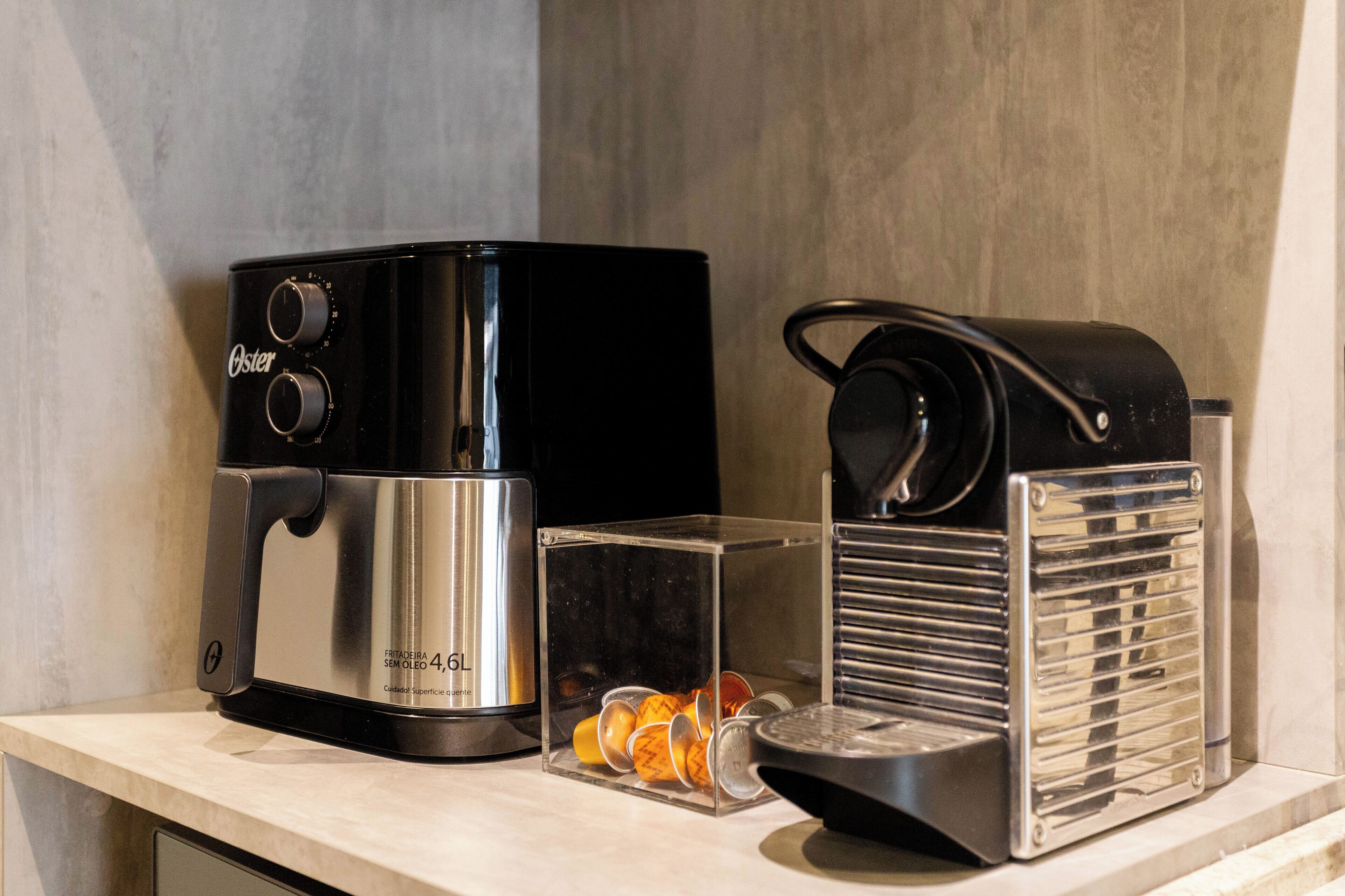 A coffee maker, a clear container with orange peels, and a metal container with a handle on a countertop.