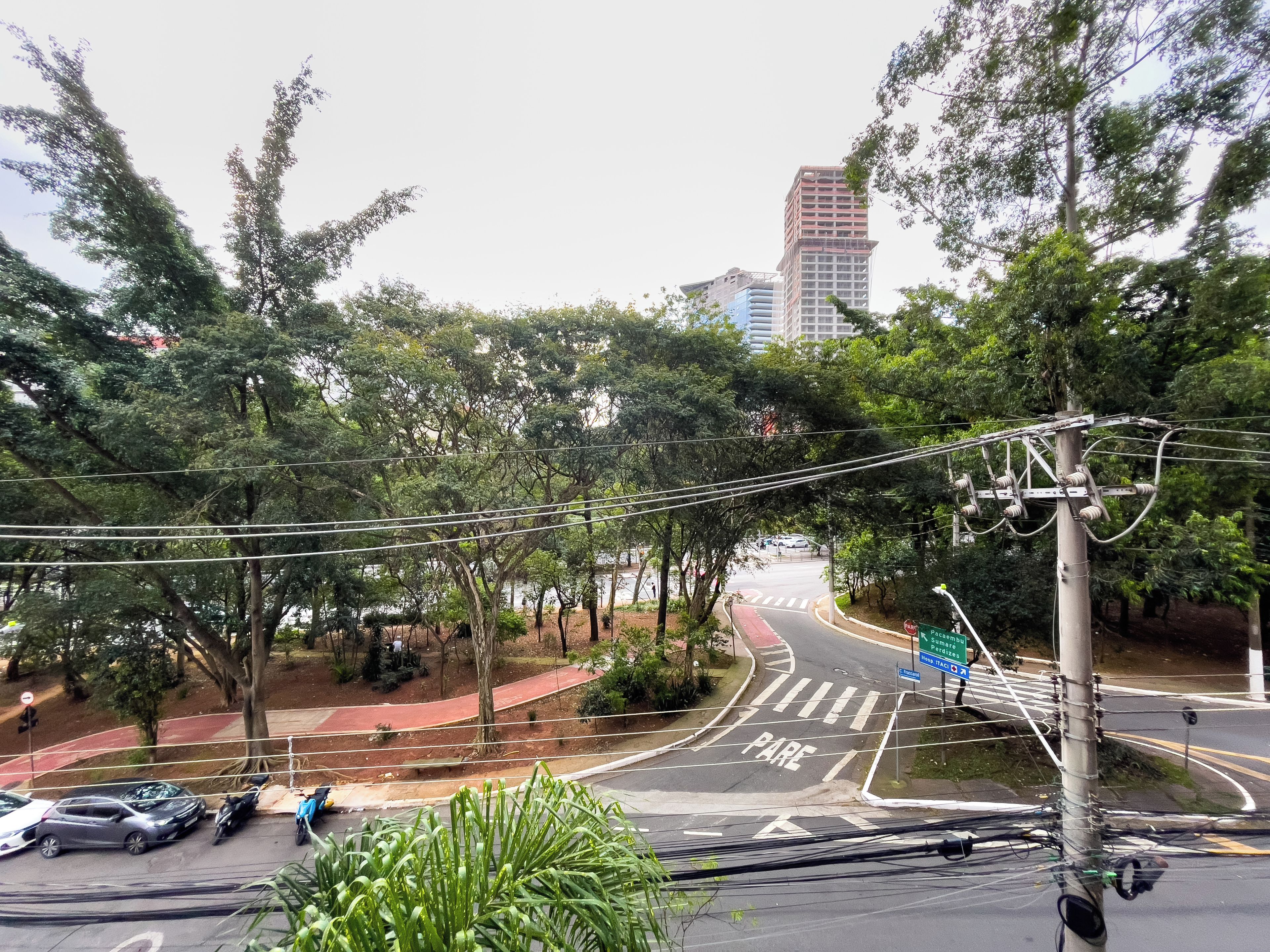 A street view with a pedestrian crossing, parked cars, and a road sign indicating a bus stop.