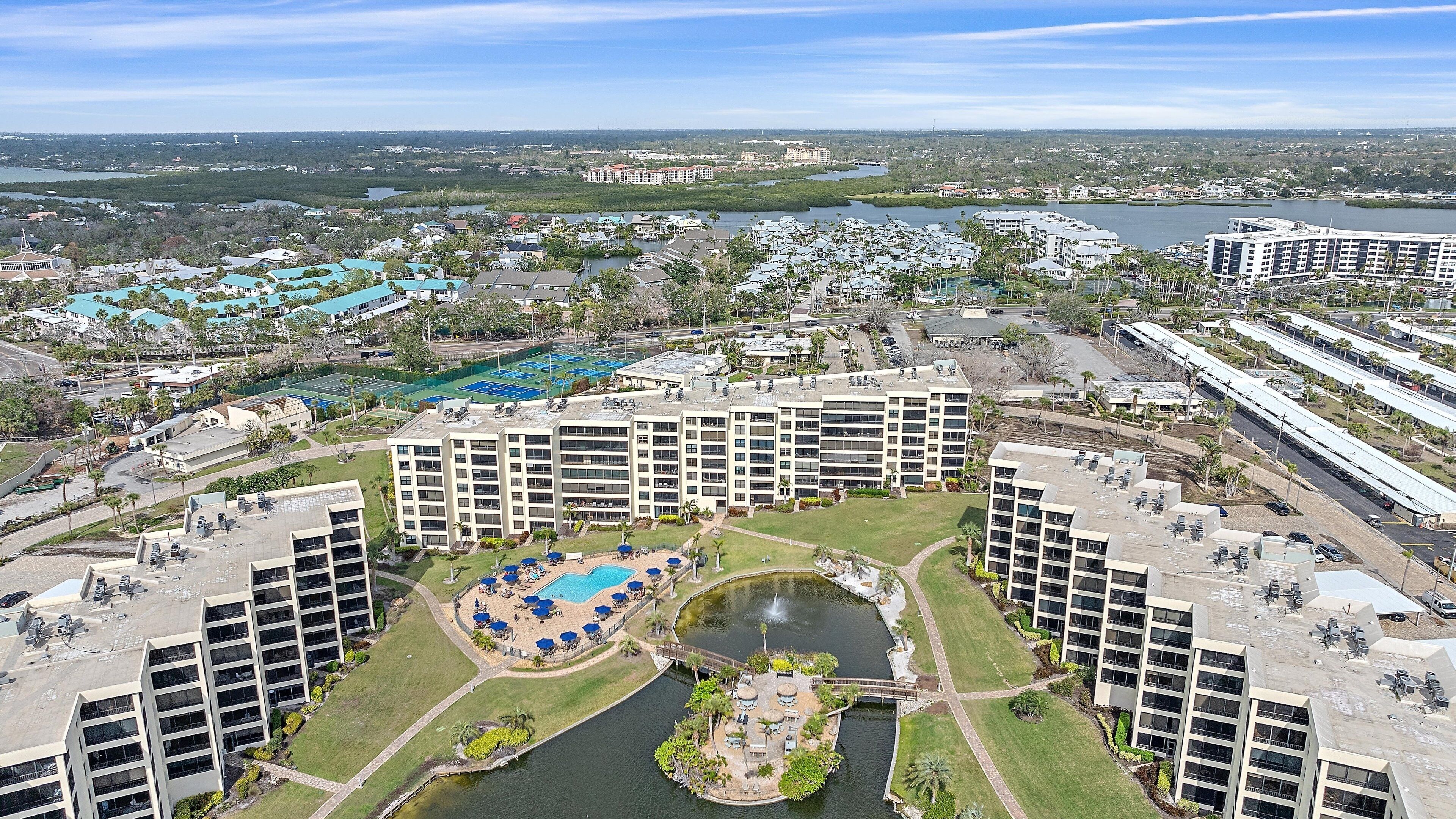 A high-rise hotel with multiple floors, a central courtyard with a swimming pool, and a view of the surrounding area including other buildings and a body of water.
