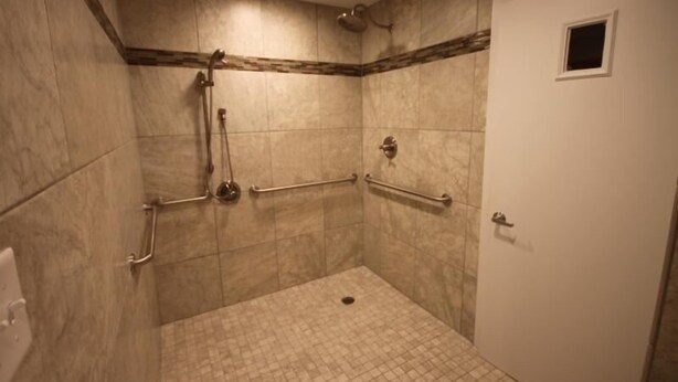 A small, enclosed shower area with a door, tiled walls, and handrails. - 147 El Matador 2 Bedroom Home (Fort Walton Beach)