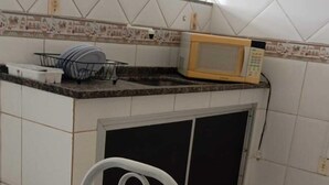 Una cocina con armarios blancos, un microondas y un lavamanos.