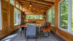 A wooden cabin interior with a dining table, chairs, and a bench.