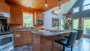 A modern kitchen with wooden cabinets, a stainless steel oven, a microwave, and a large island with bar stools.