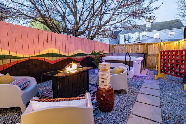Eine Terrasse im Freien mit Feuerstelle, Sitzgelegenheiten und einer dekorativen Wand.