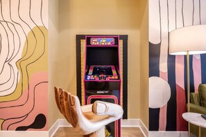 Una máquina recreativa retro en una habitación con arte abstracto en la pared y una lámpara moderna.