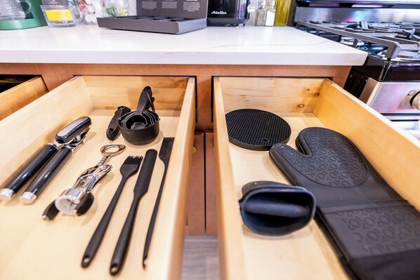A kitchen drawer with utensils and a grater.