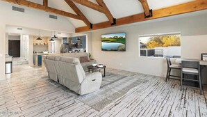 Ein geräumiges Wohnzimmer mit einer großen Couch, einem Essbereich mit Tisch und Stühlen sowie einer Küche im Hintergrund.
