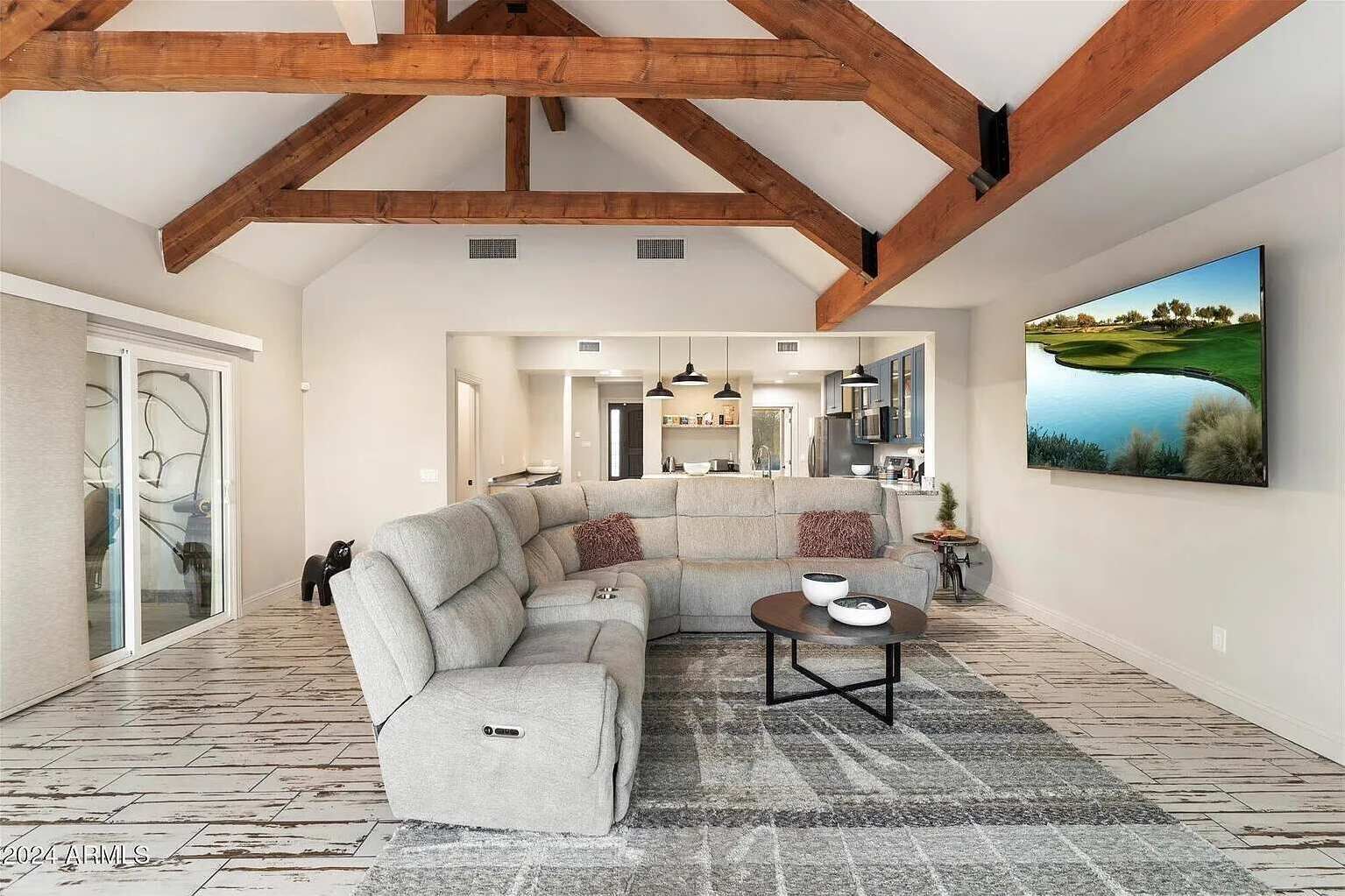 A spacious living room with a sectional sofa, a coffee table, and a large painting on the wall.