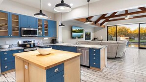 Eine moderne Küche mit blauen Schränken, einer Holztheke und Pendelleuchten.