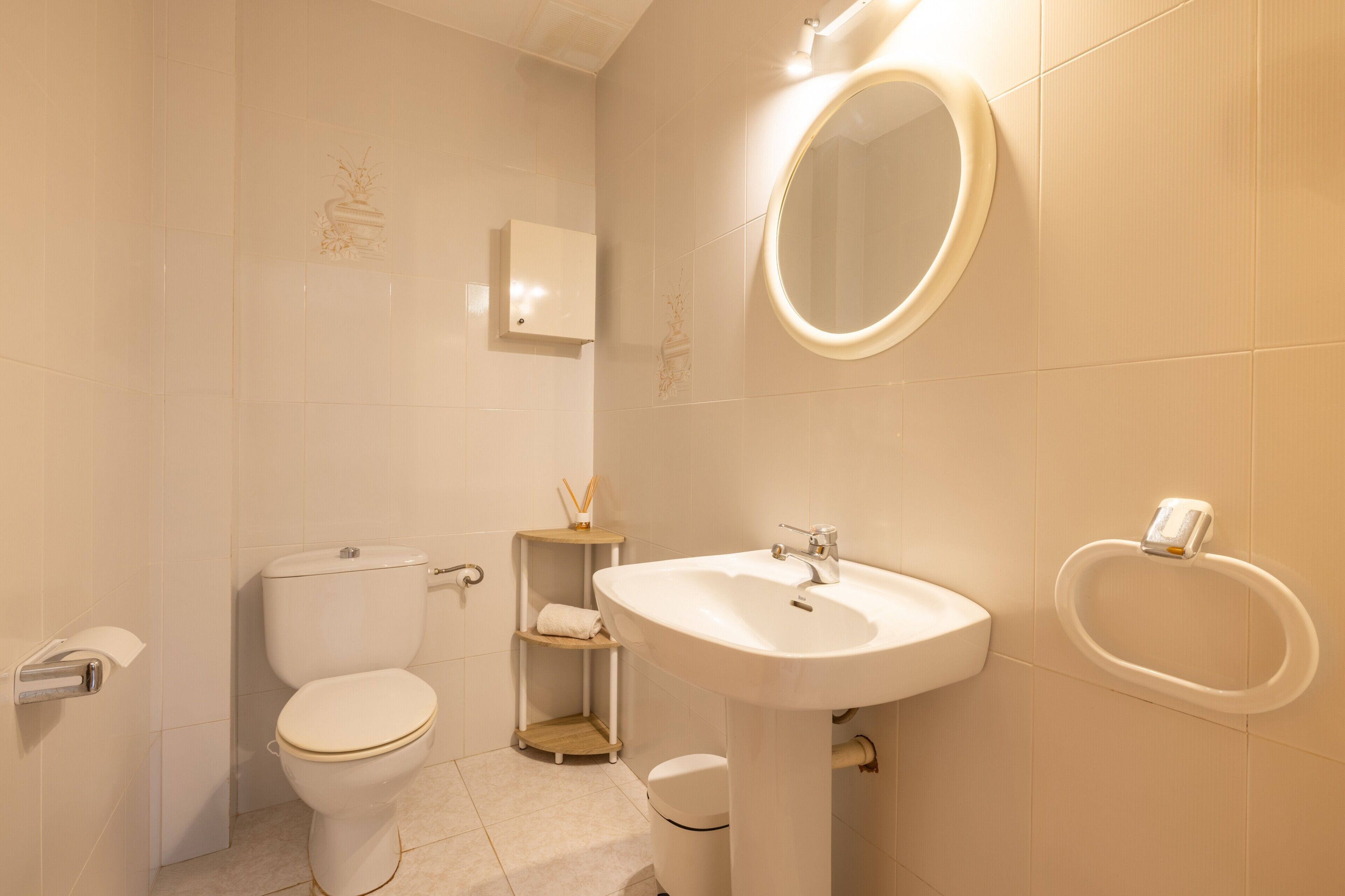 A bathroom with a toilet, sink, mirror, and towel rack.