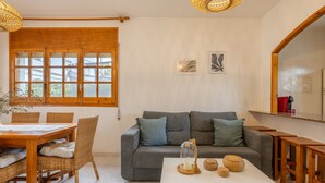 A living room with a sofa, dining table, chairs, and a coffee table. - Holiday Home 'Deltabahia' with Shared Pool, Wi-Fi and Air Conditioning (Alcanar)