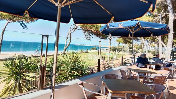 An outdoor seating area with tables and chairs, umbrellas, and a view of the beach and ocean. - Rotonda I 88 in Conil de la Frontera (Conil de la Frontera)