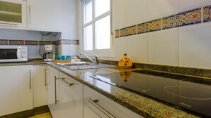 A modern kitchen with white cabinets, a microwave, a sink, and a stove. - Rotonda I 88 in Conil de la Frontera (Conil de la Frontera)