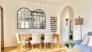 Un salon moderne avec une table basse en bois, un canapé bleu et un coin repas comprenant une table en bois et des chaises blanches.