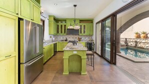 A kitchen with green cabinets, a stainless steel refrigerator, and a large island.
