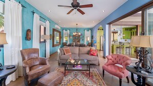 A spacious living room with a ceiling fan, a sofa, a coffee table, and a vibrant rug.