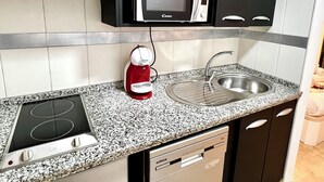 A compact kitchen with a microwave, kettle, and built-in dishwasher. - Modern apartment in Juan de Austria (Málaga)