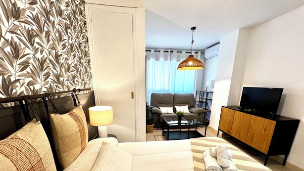 A hotel room with a bed, a desk, a chair, a television, and a wardrobe. - Modern apartment in Juan de Austria (Málaga)