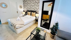 A modern bedroom with a bed, bedside tables, a mirror, a TV, and a small table with a plant. - Modern apartment in Juan de Austria (Málaga)