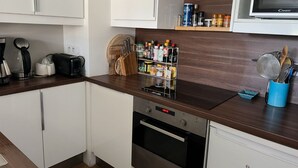 A modern kitchen with white cabinets, a Bosch dishwasher, a microwave, and a coffee maker.