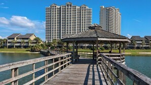 A wooden pier leading to a gazebo with a view of high-rise hotels in the background. - Sleeps 8 w/ Resort Pools, Tennis, Golf & Beach Access + Attraction Tickets! (Miramar Beach)