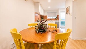 Un comedor con una mesa redonda de madera, sillas amarillas y un centro de mesa.