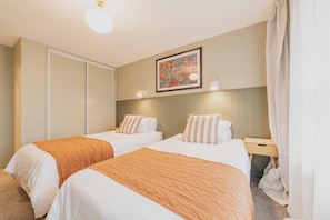 Ein Hotelzimmer mit zwei Betten, einem großen Gemälde an der Wand und einem kleinen Nachttisch mit einer Lampe.