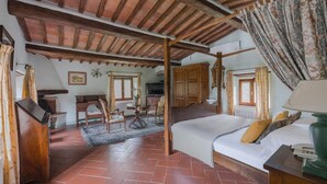 Un dormitori rústic amb sostre de fusta, un llit amb una làmpada verda i una taula amb una cadira.