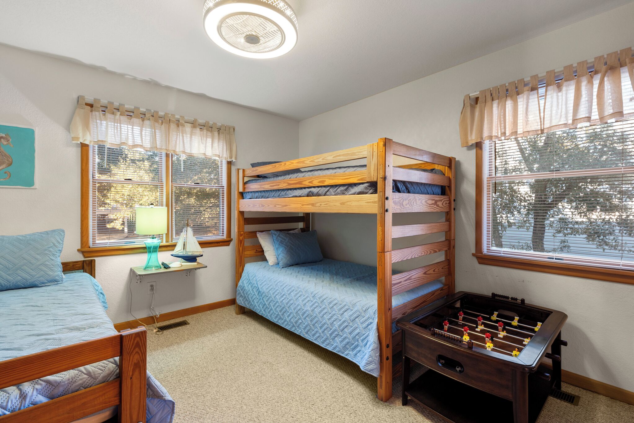 A bedroom with bunk beds, a desk, and a foosball table.