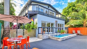 A modern two-story house with a swimming pool, outdoor seating, and lush greenery. - Orange Dream on the Water (Fort Lauderdale)