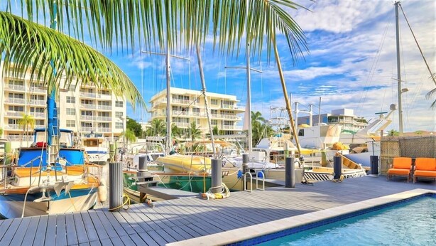 A marina with boats docked, a swimming pool, and a building with balconies. - Orange Dream on the Water (Fort Lauderdale)