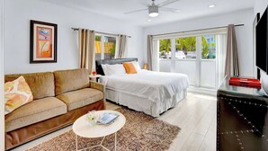 A hotel room with a bed, a sofa, a coffee table, and a TV. - Orange Dream on the Water (Fort Lauderdale)