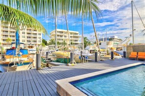 Un puerto deportivo con barcos amarrados, una piscina y un edificio con balcones.