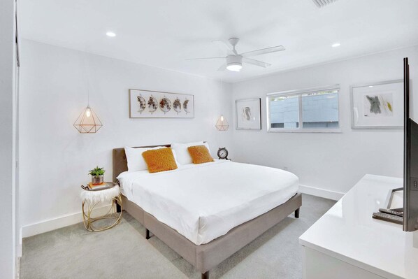 Un dormitorio moderno con una cama grande, una mesita de noche con una planta y obras de arte en las paredes.