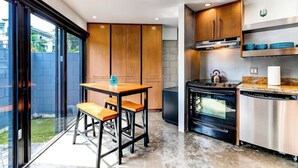 A modern kitchen with wooden cabinets, a black stove, and a dishwasher. - Las Olas Triplex w/ Water View, 5min to Beach (Fort Lauderdale)