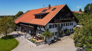 A two-story building with a red-tiled roof, a balcony with plants, and a sign that reads "Hotel". - Modern farmhouse for 10 people (Nesselwang)