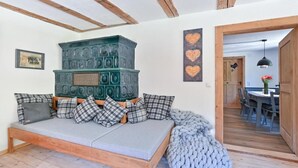 A cozy room with a wooden bench, a green decorative wall piece, and a dining area visible through an open door. - Modern farmhouse for 10 people (Nesselwang)