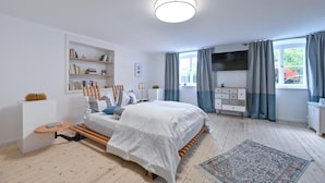 A modern bedroom with a bed, bedside tables, a bookshelf, and a large window with curtains. - Modern farmhouse for 10 people (Nesselwang)