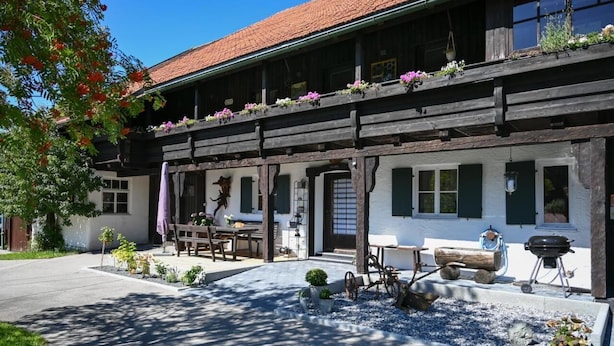 A traditional chalet with a wooden facade, outdoor seating, and a barbecue area. - Modern farmhouse for 10 people (Nesselwang)
