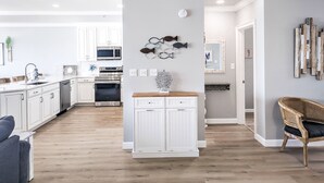Una cocina moderna con armarios blancos, electrodomésticos de acero inoxidable y una mesa de comedor de madera.