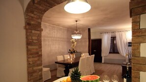 A dining area with a brick archway, a chandelier, a table set with candles, and a bottle of wine. - Lovely holiday home in Val d’Orcia, with pool and large garden, near Pienza (Pienza)