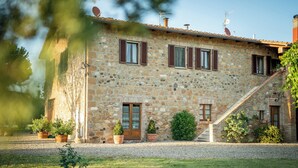 A stone building with a wooden door, windows with shutters, and a gravel driveway. - Lovely holiday home in Val d’Orcia, with pool and large garden, near Pienza (Pienza)