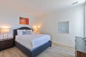 Cozy retreat with a large bed, dark headboard, and matching nightstand, complete with a lamp and framed artwork.
