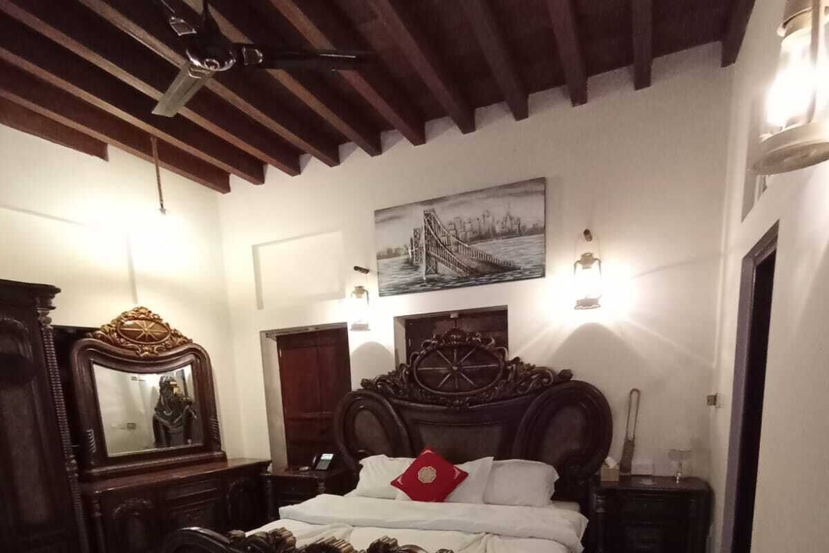 A bedroom with a large bed, wooden headboard, a mirror, and a painting on the wall.