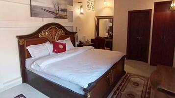 A bedroom with a wooden bed, a nightstand, a mirror, and a ceiling fan.