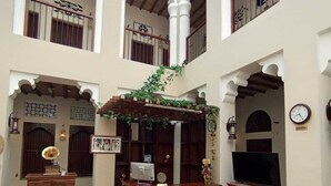 Un vaste atrium doté d’un comptoir d’accueil central, de meubles en bois et d’éléments décoratifs tels que des plantes et des motifs traditionnels.