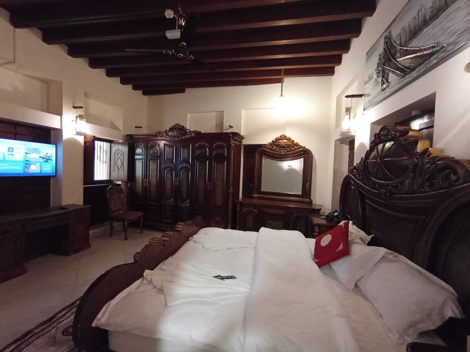 A bedroom with a bed, a television, a wardrobe, and a mirror.
