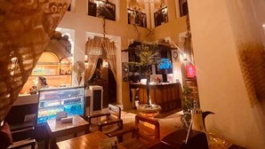 Un intérieur chaleureux et accueillant, éclairé d’une lumière douce, avec des meubles en bois, un comptoir d’accueil et un espace bar.