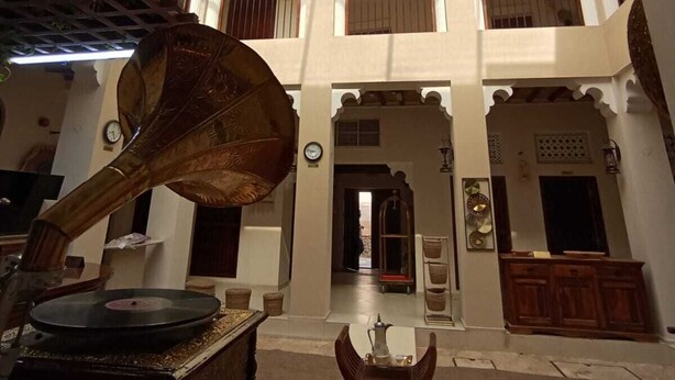 Un intérieur spacieux avec un plafond haut, des fenêtres en arc de cercle et un espace central agrémenté d’une platine vinyle.
